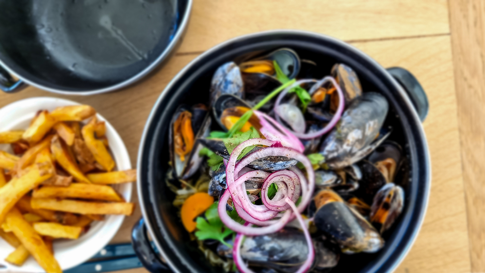A,Pot,Of,Freshly,Cooked,Mussels,Garnished,With,Purple,Onion